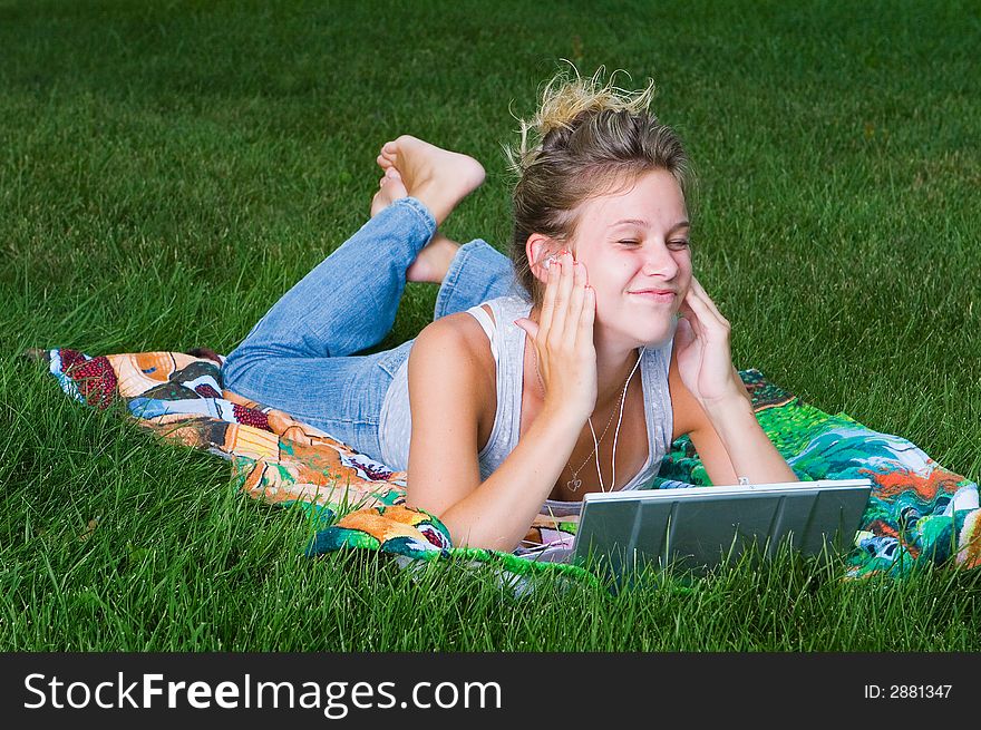 A young girl relaxing with her mp3 player and laptop. A young girl relaxing with her mp3 player and laptop