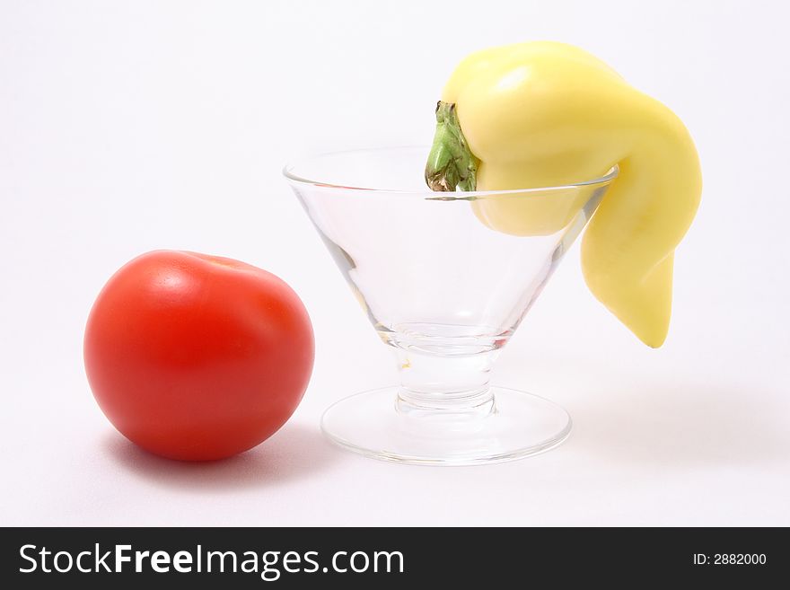 Tomato and a yellow paprika in a cocktail glass on a white background