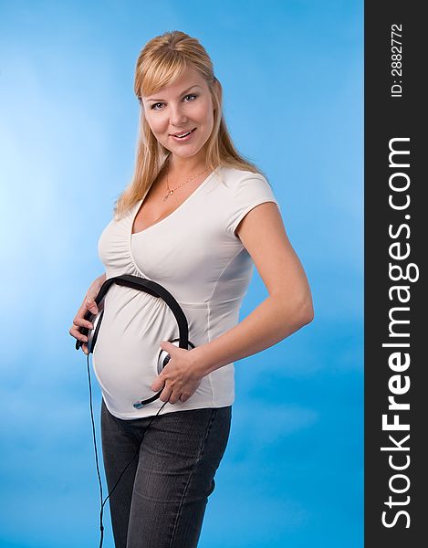 The beautiful pregnant woman with headphones on a stomach. The beautiful pregnant woman with headphones on a stomach.