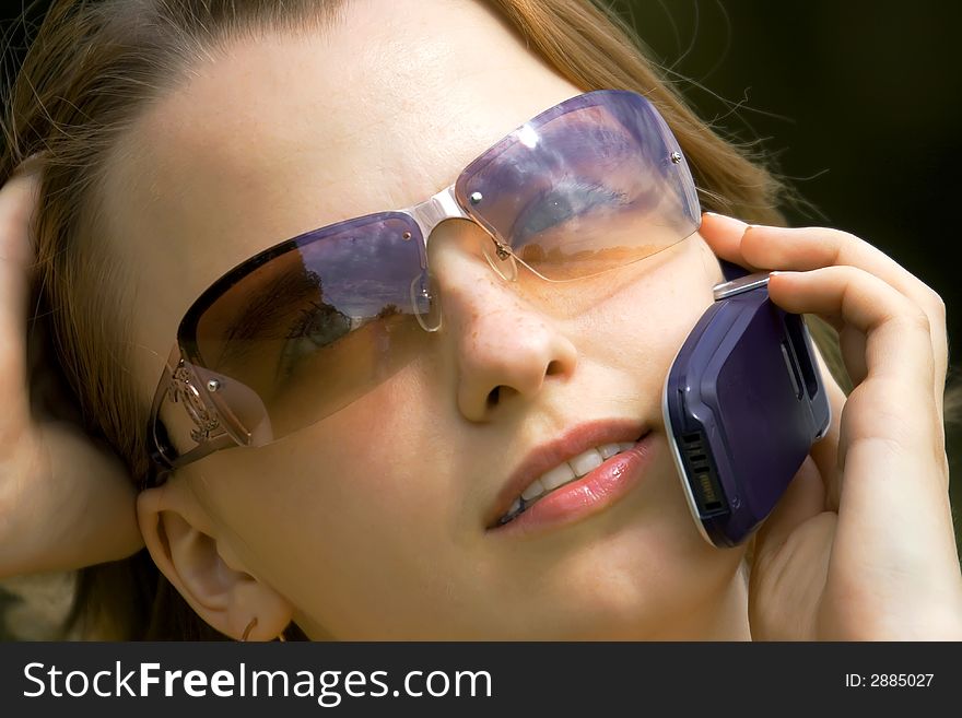 Portrait of the young girl in glasses speaking by phone. Portrait of the young girl in glasses speaking by phone