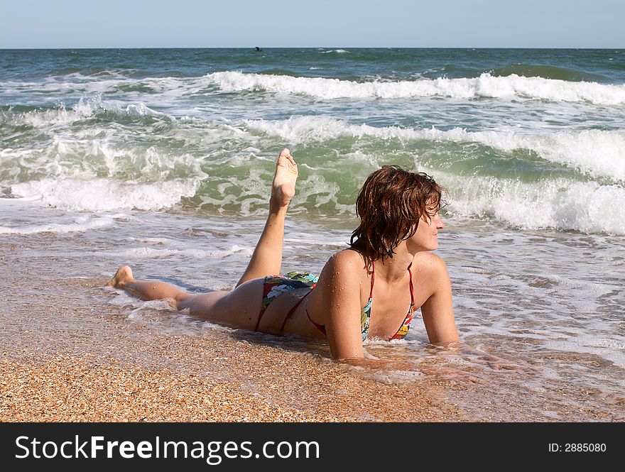 Girl in bikini in the waves on the sand beach