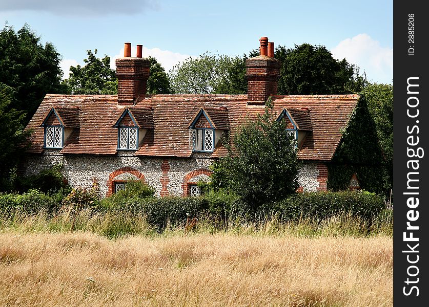 Brick and Flint House in a Rural Village in England with a hedge and Meadow to the front
