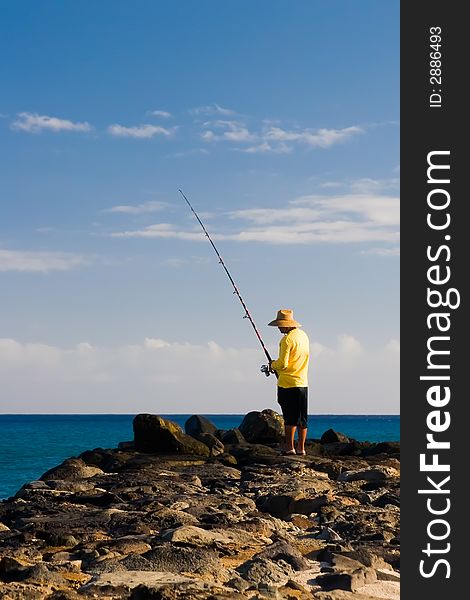 Shore fisherman angling off a rock wall for the catch of the day. Shore fisherman angling off a rock wall for the catch of the day