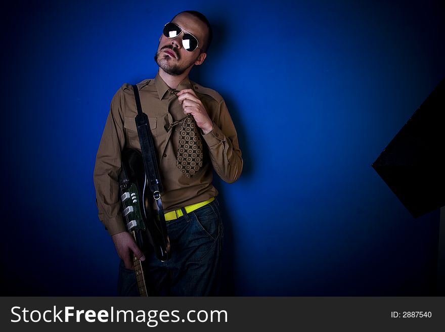 Guitar player relaxing between takes, loosening his tie. Candid style shot. Guitar player relaxing between takes, loosening his tie. Candid style shot.