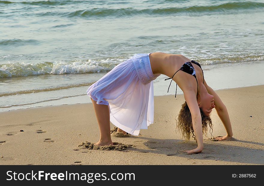 Woman stretching to a bridge at the beach. Woman stretching to a bridge at the beach