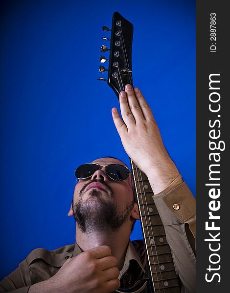 Guitar player with sunglasses in studio, posing with his guitar. Guitar player with sunglasses in studio, posing with his guitar.