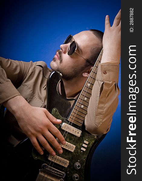 Guitar player with sunglasses in studio, posing with his guitar. Guitar player with sunglasses in studio, posing with his guitar.