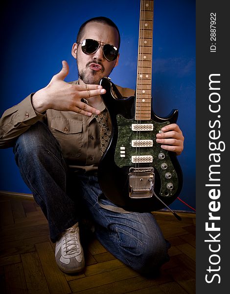 Guitar player with sunglasses in studio, posing with his guitar. Guitar player with sunglasses in studio, posing with his guitar.