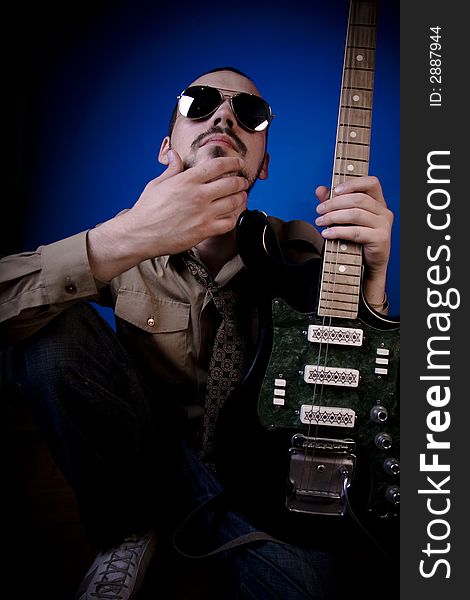 Guitar player with sunglasses in studio, looking smugly at the camera. Guitar player with sunglasses in studio, looking smugly at the camera.