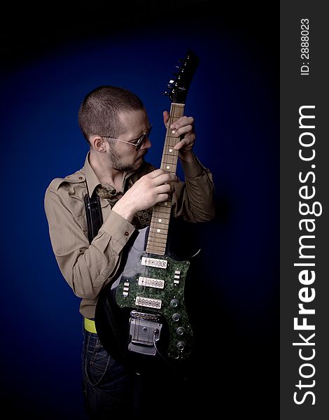 Guitar player with sunglasses in studio, jamming. Blue background. Guitar player with sunglasses in studio, jamming. Blue background.