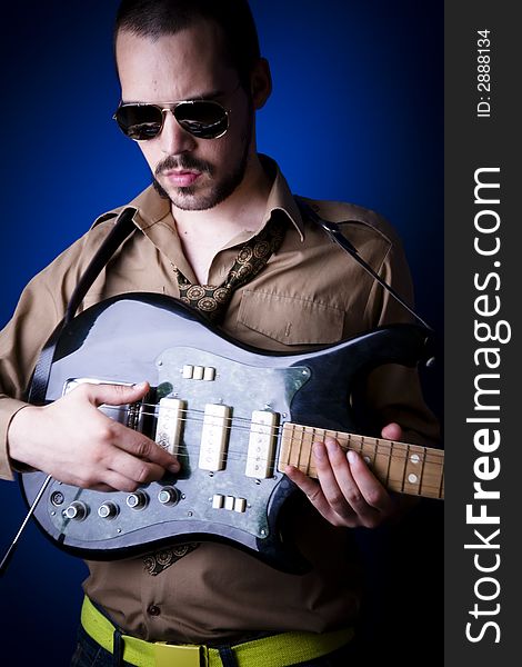 Guitar player with sunglasses in studio, jamming. Blue background. Guitar player with sunglasses in studio, jamming. Blue background.