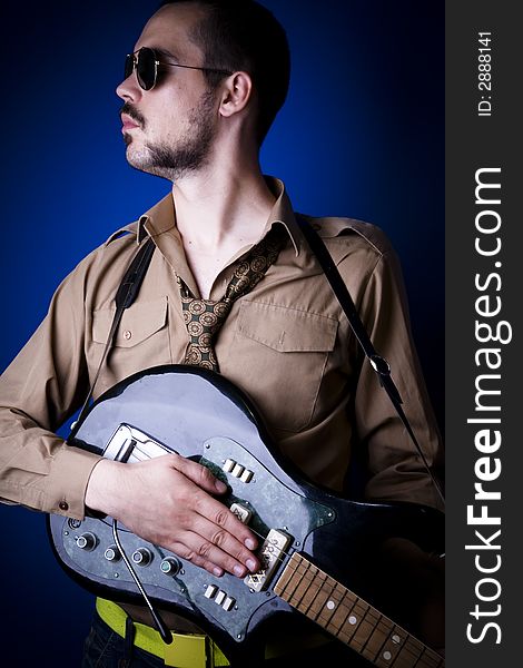 Electric guitar player with sunglasses in studio against a blue wall. Electric guitar player with sunglasses in studio against a blue wall.