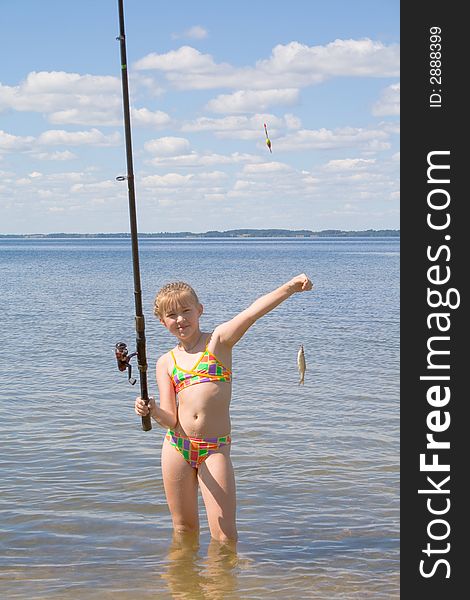 Girl holding a fish caught on a fishing line with clouds. Girl holding a fish caught on a fishing line with clouds