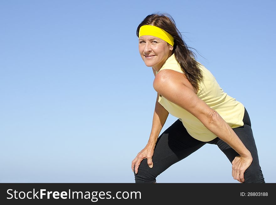 Portrait fit and healthy, confident and determined attractive looking mature woman exercising, with blue sky as background and copy space. Portrait fit and healthy, confident and determined attractive looking mature woman exercising, with blue sky as background and copy space.
