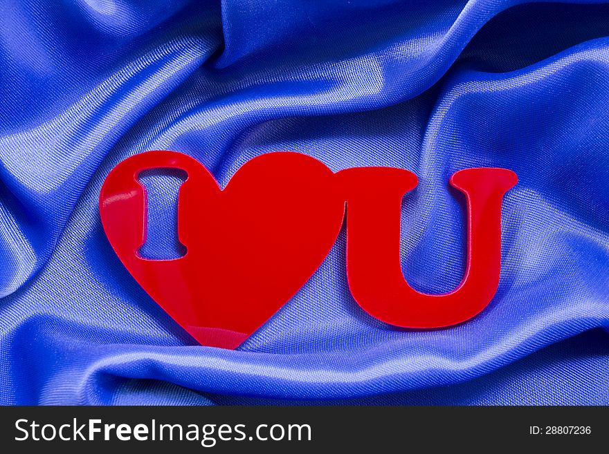 I love you red shape of a plexiglas material on a blue silk background.