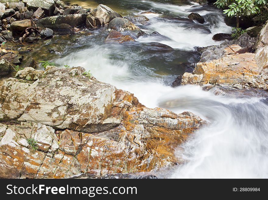 The flowing of waterfall  on big rock that be full of moss