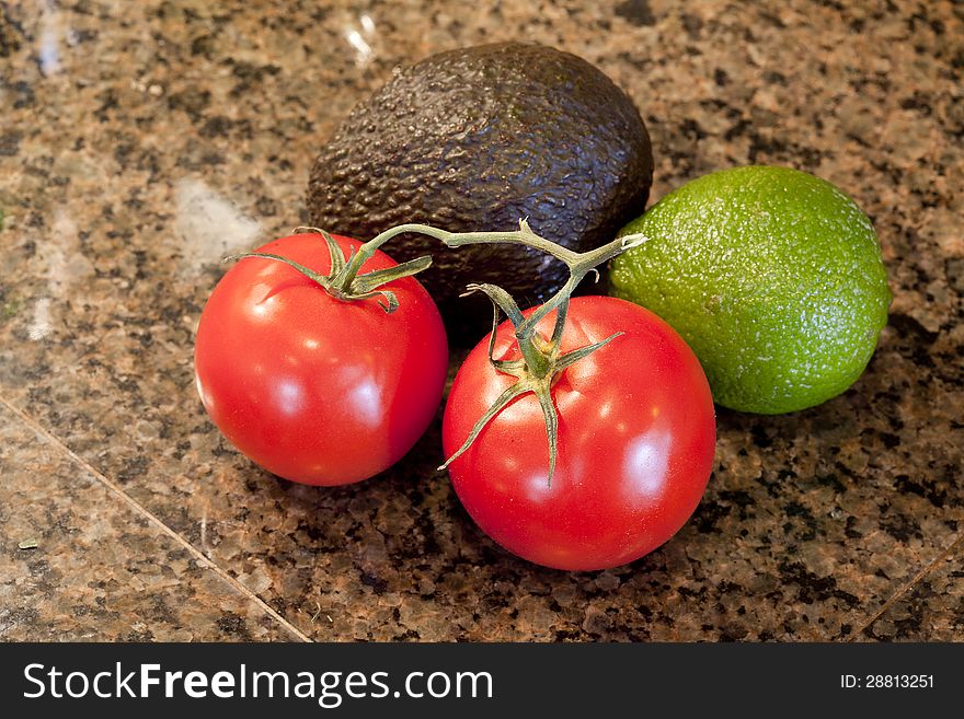 Tomatoes, avocado, and lime on a granite countertop. Tomatoes, avocado, and lime on a granite countertop.