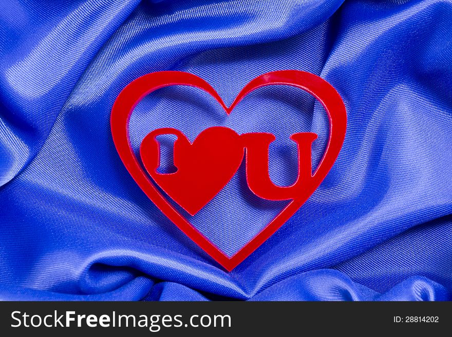 I love you red shape of a plexiglas material inside of other red heart shape on a blue silk background. I love you red shape of a plexiglas material inside of other red heart shape on a blue silk background.