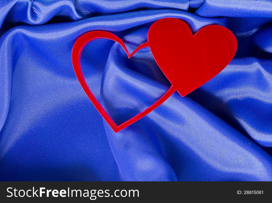 Two red hearts on a blue silk background. Two red hearts on a blue silk background.