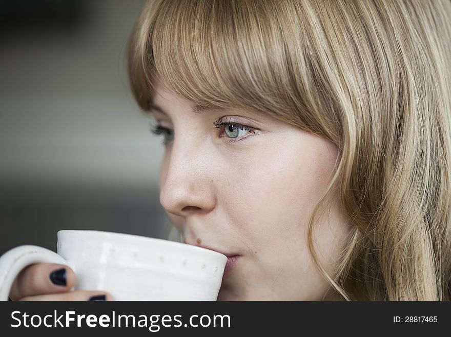 Portrait of a young woman looking away from the camera holding a cup of coffee. Portrait of a young woman looking away from the camera holding a cup of coffee.