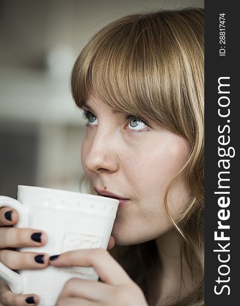 Portrait of a young woman looking up while holding a cup of coffee. Portrait of a young woman looking up while holding a cup of coffee.