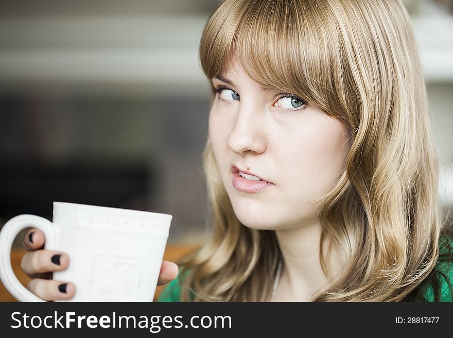 Portrait of a young woman making an ugly face and holding a cup of coffee. Portrait of a young woman making an ugly face and holding a cup of coffee.