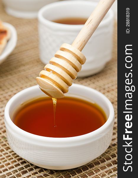 Bowl of honey with wooden dipper on the table closeup. Bowl of honey with wooden dipper on the table closeup