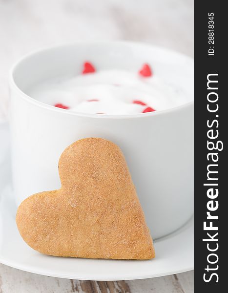 Cup of hot milk with foams and heart-shaped cookies, closeup. Cup of hot milk with foams and heart-shaped cookies, closeup