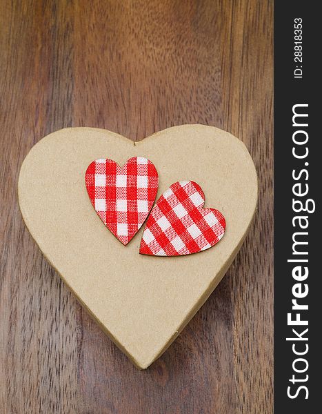 Decorative gift cardboard box with hearts on a wooden background. Decorative gift cardboard box with hearts on a wooden background