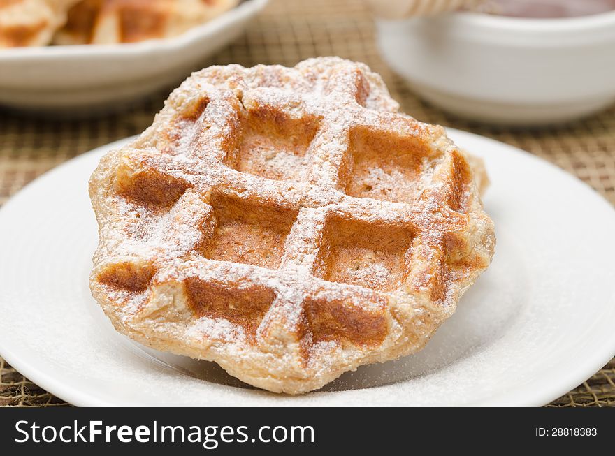 Homemade waffles topped with powdered sugar on a white plate for breakfast closeup. Homemade waffles topped with powdered sugar on a white plate for breakfast closeup