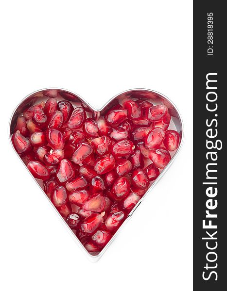 Pomegranate seeds in heart shape in white baking dish isolated. Pomegranate seeds in heart shape in white baking dish isolated