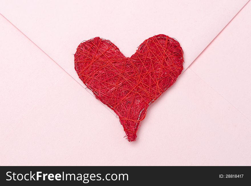 Red heart on a pink envelope closeup