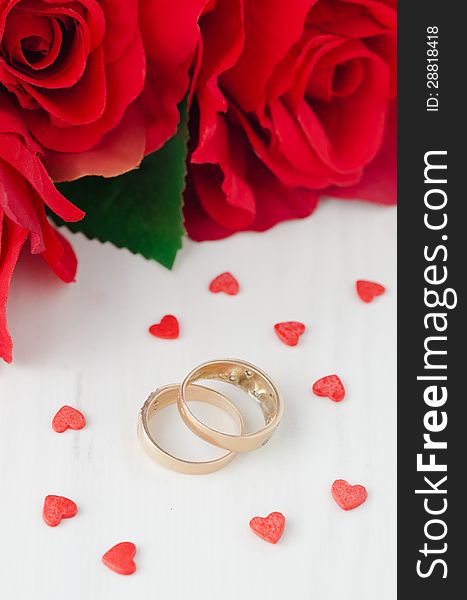 Red roses, rings and sugar hearts for Valentine's Day on a white table. Red roses, rings and sugar hearts for Valentine's Day on a white table