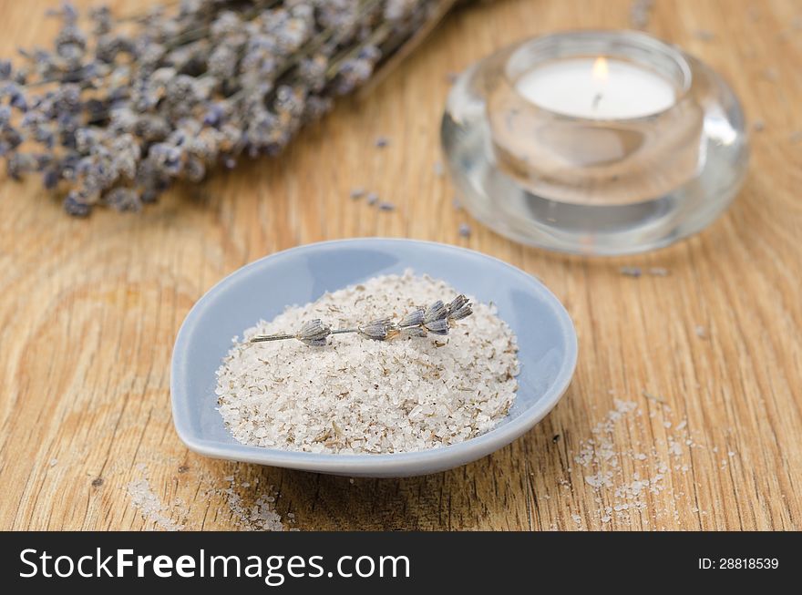 Sea salt with lavender in a blue bowl and candle on wooden table. Sea salt with lavender in a blue bowl and candle on wooden table