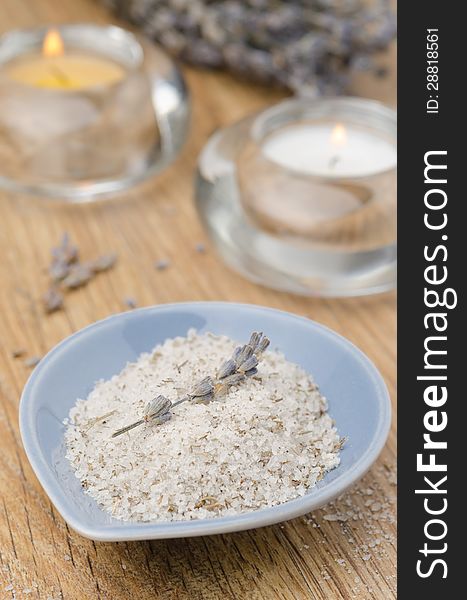 Sea salt with lavender in a blue bowl and two candles on the wooden table. Sea salt with lavender in a blue bowl and two candles on the wooden table