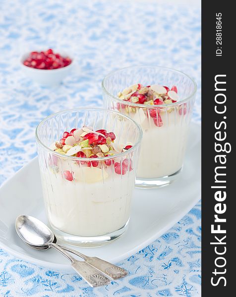 Semolina dessert with pomegranate seeds and pistachios in glass beakers on a plate