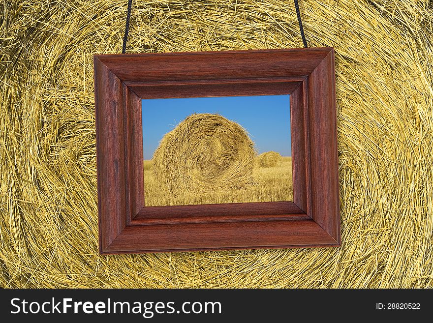 Picture in wooden frame hanging on the background stack of hay. Picture in wooden frame hanging on the background stack of hay