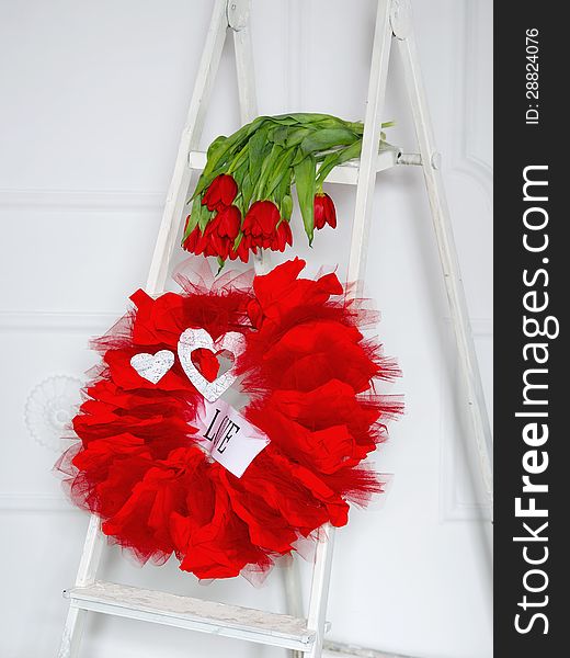 Love garland and red tulips lying down on a white ladder. Love garland and red tulips lying down on a white ladder