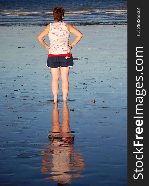 Woman s reflection in wet sand on Australian beach