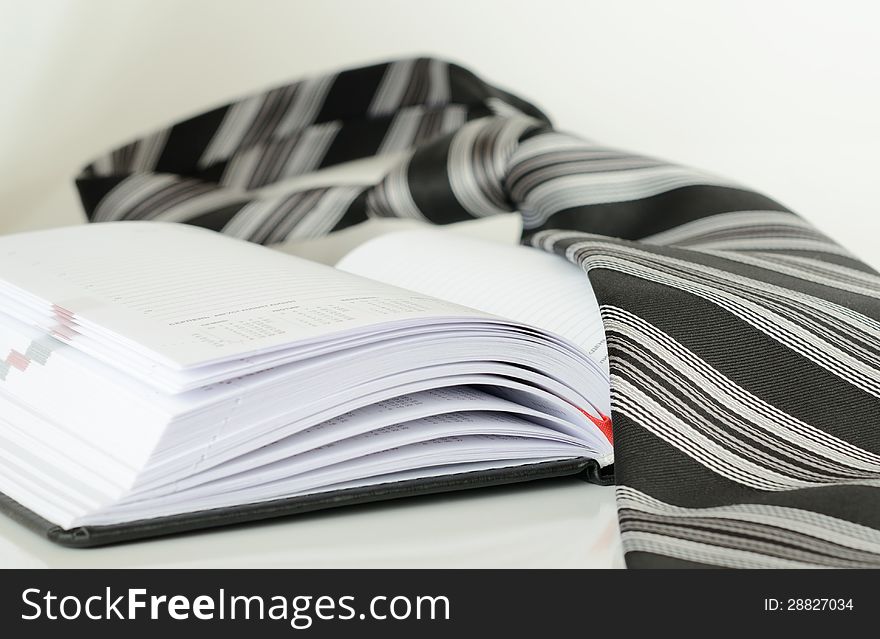 Striped black and white tie on an opened diary. Striped black and white tie on an opened diary