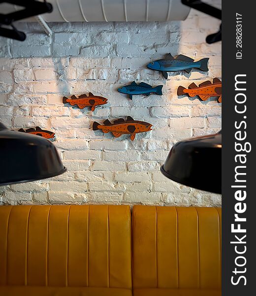 Multi-colored fish figures on a white brick wall above a yellow sofa