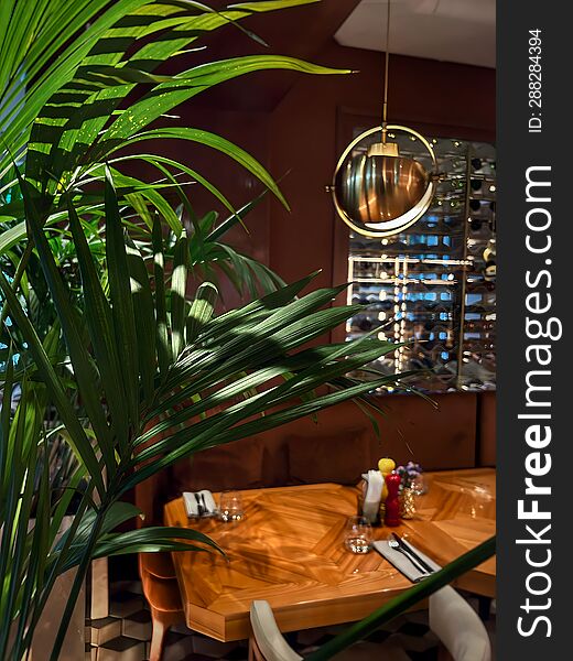 Green Flower In Dark Restaurant Interior In Front Of Lamp And Table