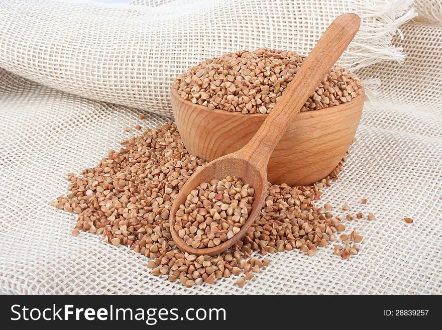 Raw buckwheat in wooden bowl and spoon on burlap, food ingredient photo