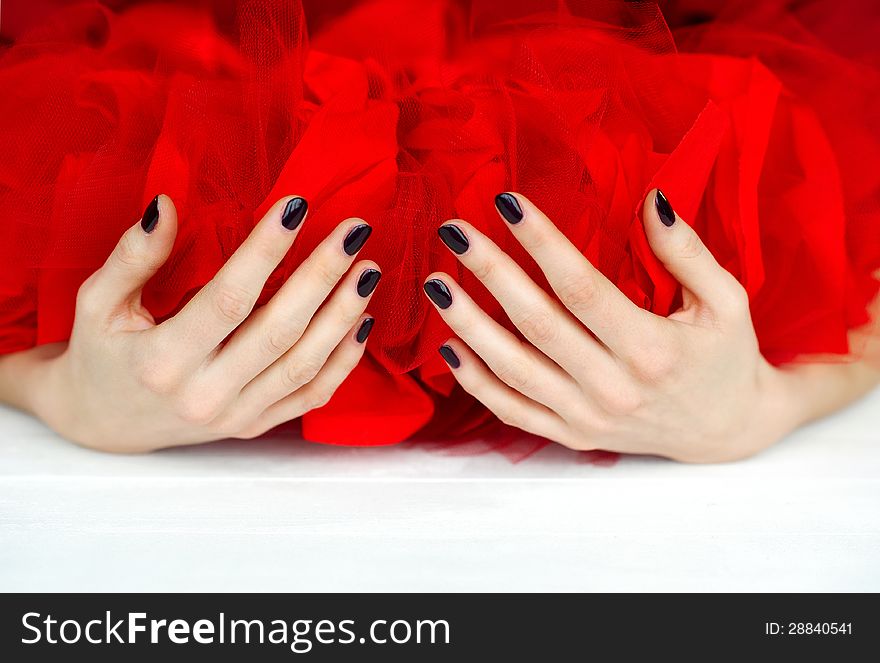 Cupped hands with dark manicure holding bright red cloth. Cupped hands with dark manicure holding bright red cloth