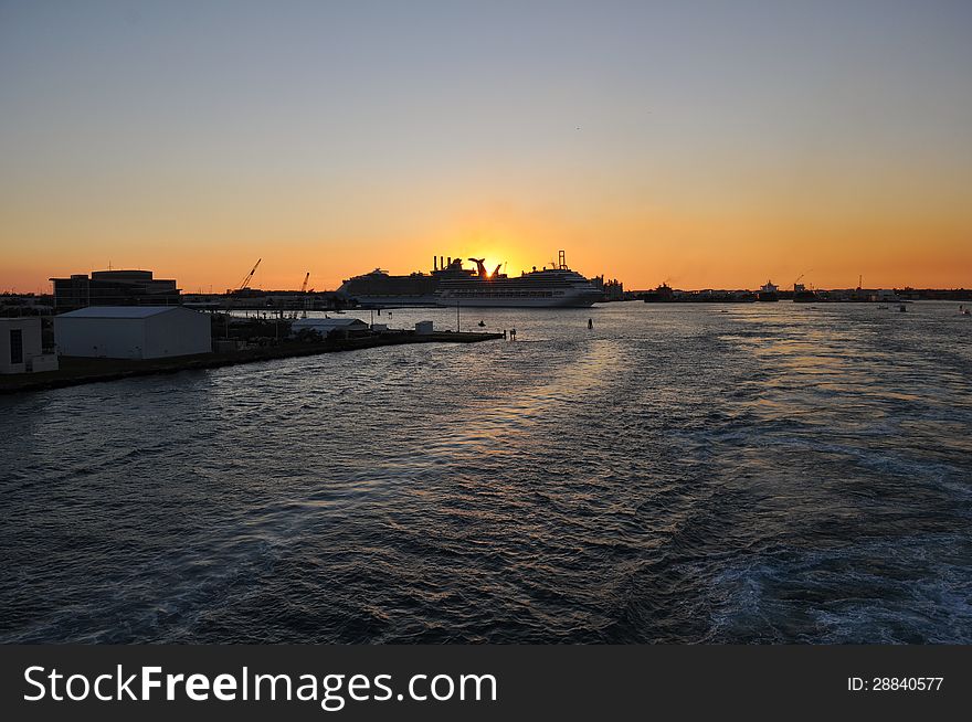 Sun setting over fort lauderdale cruise terminal from a moving cruise ship heading out to sea. Sun setting over fort lauderdale cruise terminal from a moving cruise ship heading out to sea