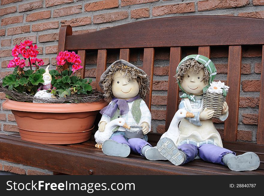 Garden dolls on the wooden bench in front of house. Garden dolls on the wooden bench in front of house