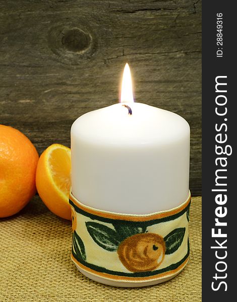 A candle decorated with a nice ribbon and clementines, rustic still-life. A candle decorated with a nice ribbon and clementines, rustic still-life