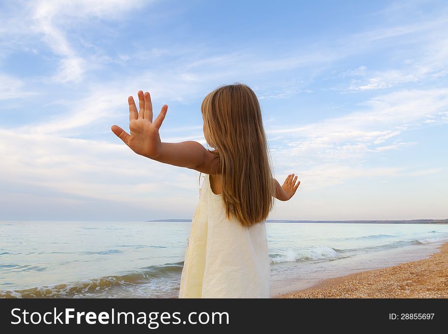 Small cute girl in white dress enjoying sunny day at the beach. Small cute girl in white dress enjoying sunny day at the beach