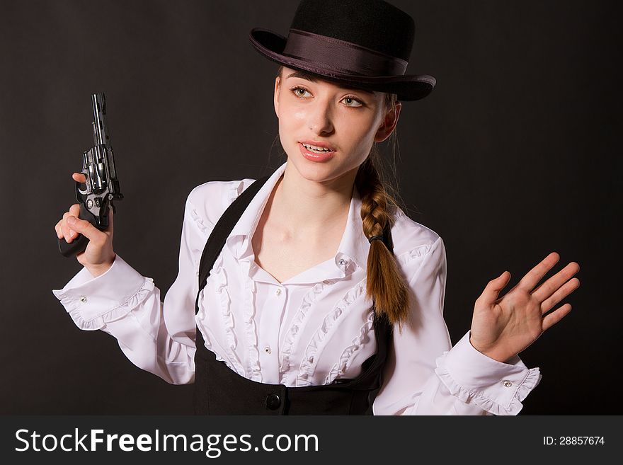 Portrait of beautiful young woman with a gun. Closeup in studio.