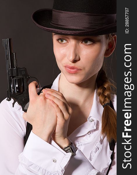 Portrait of beautiful young woman with a gun. Closeup in studio.
